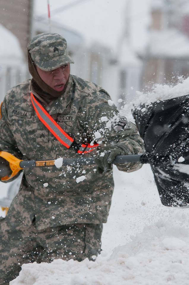 Army Sgt. Miguel Familla shovels snow away from a fire