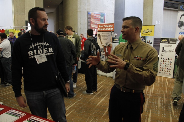 Staff Sgt. Adam Halter, Marine Corps Recruiting Station Kansas City, Recruiting Sub-Station St. Joseph staff noncommissioned officer-in-charge, speaks with a coach about the Combat Fitness Test during the Glazier Clinic at the Westin Crown Center Feb. 6, 2015. The CFT is used to test both the physical endurance as well as mental endurance of Marines. It is in this way that coaches may request recruiters to come to their schools and perform the CFT with their players to determine how effective their own conditioning programs have worked and also to build teamwork through several events outside of the normal routine of football practice.