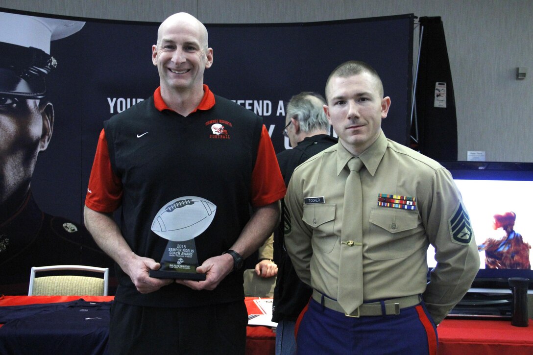 Jason Swift, Shawnee Heights High School Thunderbirds head football coach, stands with Staff Sgt. Skyler Tooker, a Marine Corps Recruiting Station Kansas City, Recruiting Sub-Station Topeka canvassing recruiter, after being presented the Semper Fi Coach Award during the Glazier Clinic at the Westin Crown Center Feb. 6, 2015. Swift was presented the award not just for his on-the-field accomplishments but the way he has influenced players in his community and molded their character on and off the field. Swift has led the Thunderbirds to eight district championships and 10 straight playoff appearances in his 12 years as head coach.