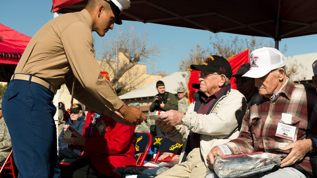 Private Miguel Ramirez, a Marine awaiting training to become a field artillery cannonier, presents a piece of cake to a veteran of Iwo Jima during a ceremony performed by the Marines of the Marine Artillery Detachment at Fort Sill, Oklahoma February 12, 2015. The Marine Artillery Detachment perfomed a ceremony to honor the veterans and provided a barbeque meal afterward.
