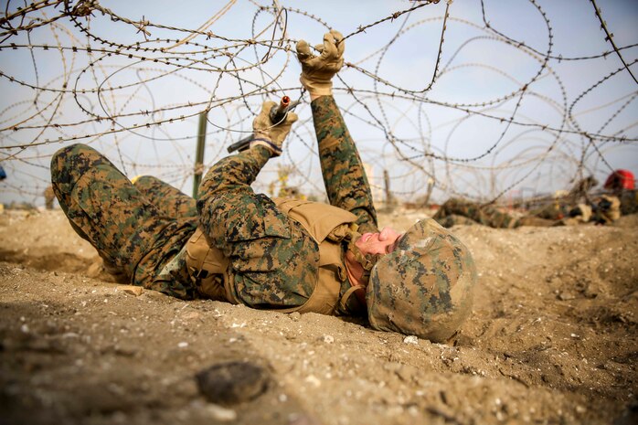 A recruit of Bravo Company, 1st Recruit Training Battalion, low crawls under barbed wire during a bayonet assault course at Marine Corps Recruit Depot San Diego, Feb. 2. Recruits were instructed to hold their weapons correctly throughout the exercise to maintain proper weapon control.