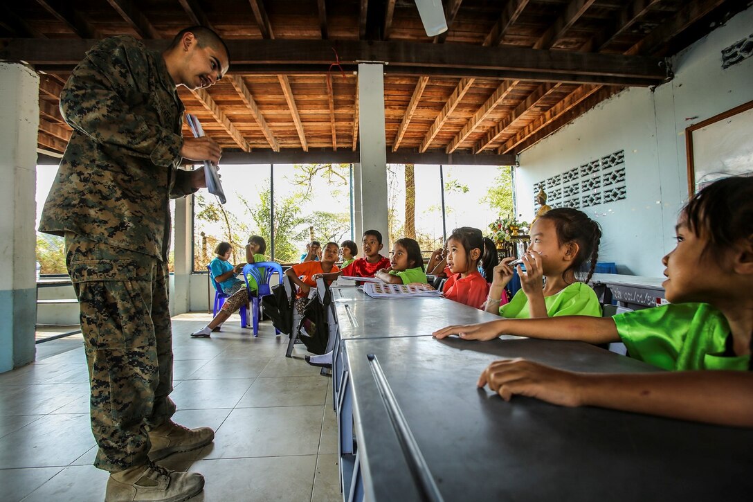 Petty Officer 3rd Class Jonathan Fuentes, a hospitalman with Marine Wing Support Squadron 171 teaches an English lesson to local kids in the district of Khok Samrong, Lop Buri province, Kingdom of Thailand, Feb. 10, 2015. MWSS-171, along with members of the Royal Thai Army and Malaysian Army, is in the process of building a multipurpose structure for the local school as part of Exercise Cobra Gold 2015. CG 15 is a combined-forces exercise taking place across Thailand from Feb. 9-20 and is designed to advance regional security and ensure effective responses to crises in the region. It includes a specific focus on humanitarian civic action, community engagement and medical activities to support the needs and humanitarian interests of the civilian population around the region. (U.S. Marine Corps Photo By Cpl. Ricardo Hurtado / Released)