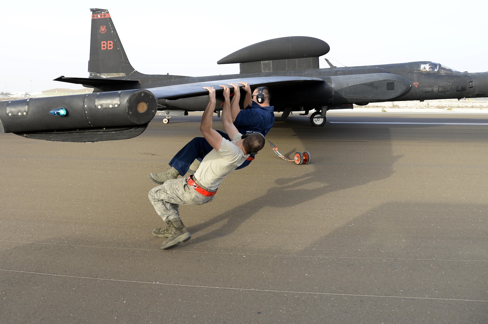 Senior Airman Alex, front, and Staff Sgt. Ruben, Dragon Aircraft Maintenance Unit, balance the weight of a U-2 Dragon Lady to install pogo wheels for taxi at an undisclosed location in Southwest Asia Feb. 9, 2015. The U-2 Dragon Lady delivers critical imagery and signals intelligence to decision makers throughout all phases of conflict, including peacetime indications and warnings, low-intensity conflict, and large-scale hostilities. Alex and Ruben are currently deployed from Beale Air Force Base, Calif. (U.S. Air Force photo/Tech. Sgt. Marie Brown)