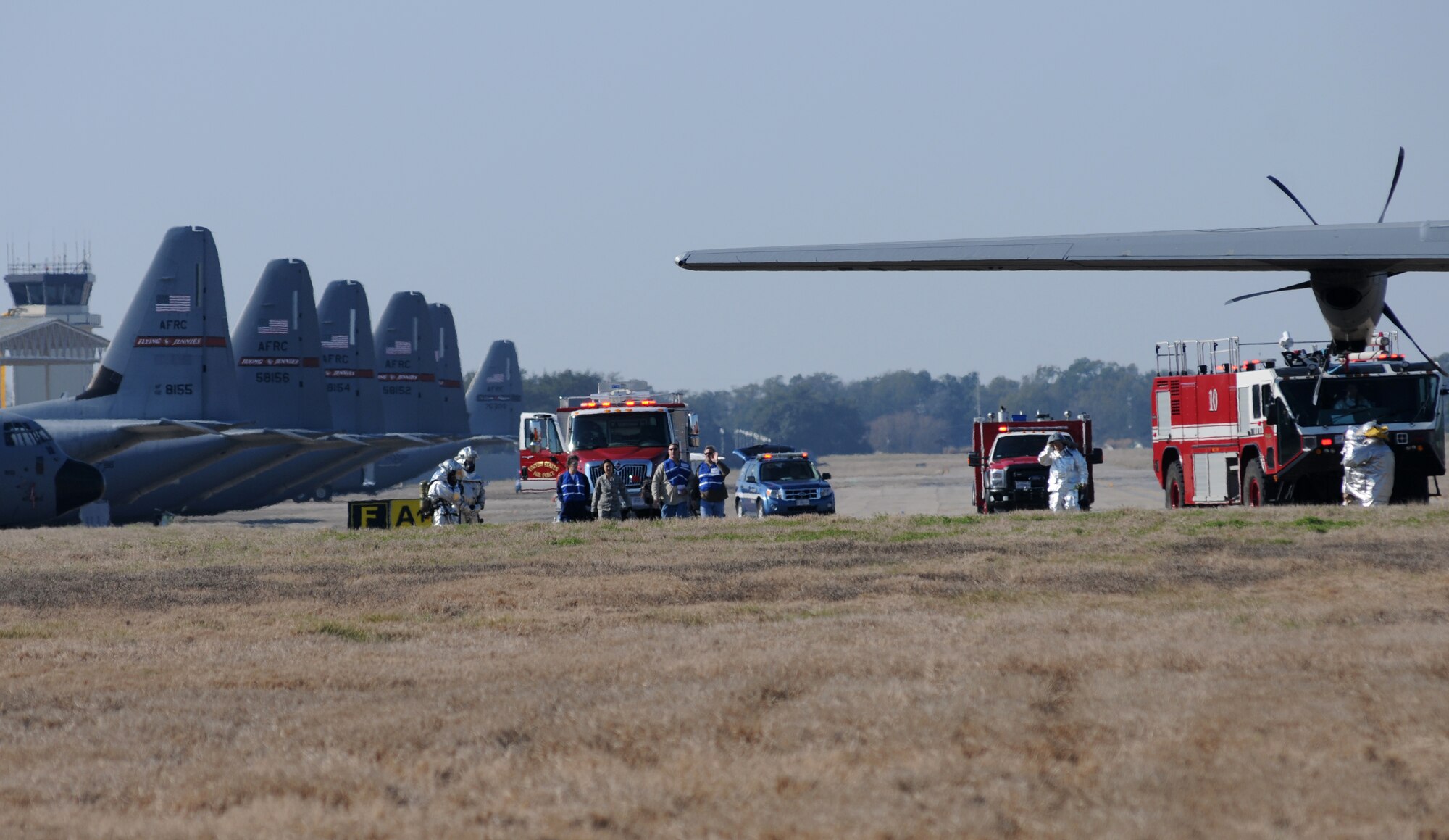 Wing inspection team members assess the area as Keesler firefighters respond during a major accident response exercise Feb. 12, 2015, on the flight line, Keesler Air Force Base, Miss.  The MARE simulated a C-130J Hercules aircraft crash on base. Exercises are held periodically to prepare for real world emergencies.  (U.S. Air Force photo by Kemberly Groue)