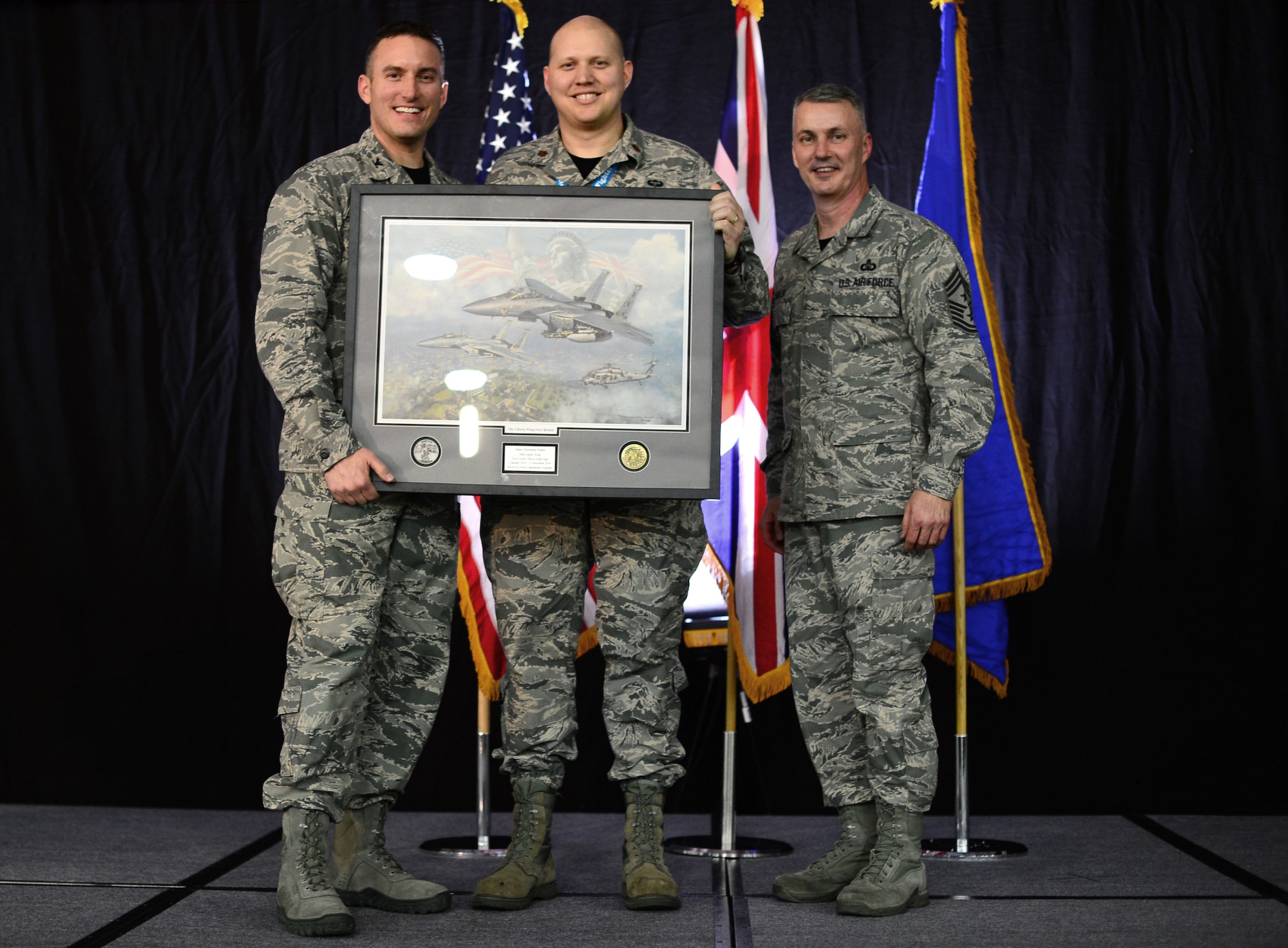 Col. Robert Novotny, 48th Fighter Wing commander, and Chief Master Sgt. Vincent Marler, 48th Fighter Wing command chief, present the Field Grade Officer of the Year Award to Maj. Christopher Pustka, 48th Maintenance Group, during the 48th FW Annual Awards Banquet at Hangar 7, Feb. 13, 2015. Airmen were recognized across 11 categories, representing the spectrum of the Liberty Wing. (U.S. Air Force photo by Airman 1st Class Erin R. Babis)