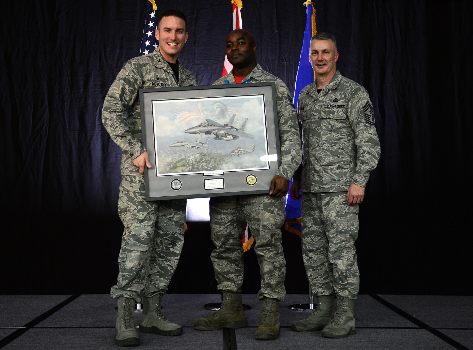 Col. Robert Novotny, 48th Fighter Wing commander, and Chief Master Sgt. Vincent Marler, 48th Fighter Wing command chief, present the NCO of the Year Award to Tech. Sgt. Thomas Williams, 48th Maintenance Group, during the 48th FW Annual Awards Banquet at Hangar 7, Feb. 13, 2015. Airmen were recognized across 11 categories, representing the spectrum of the Liberty Wing. (U.S. Air Force photo by Airman 1st Class Erin R. Babis)