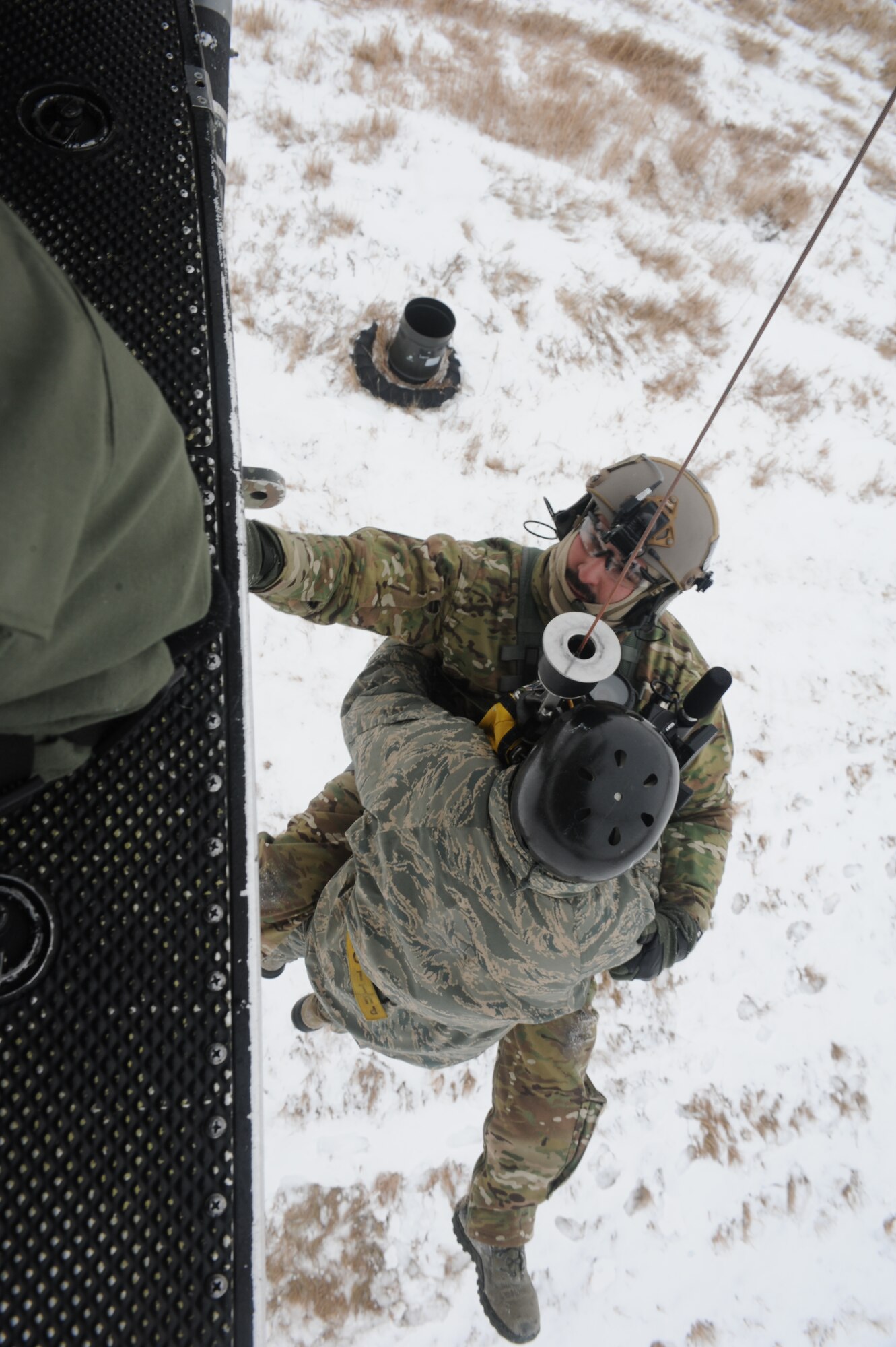 Tech. Sgt. Thomas Liscomb, 54th Helicopter Squadron flight engineer, secures an airman on a hoist as they’re lifted into a UH1-N helicopter near Minot Air Force Base, N.D., Feb. 11, 2015. Liscomb ensured that the Airman was safely seated and lifted into the aircraft as part of a search and rescue training. (U.S. Air Force photos/Senior Airman Stephanie Morris)