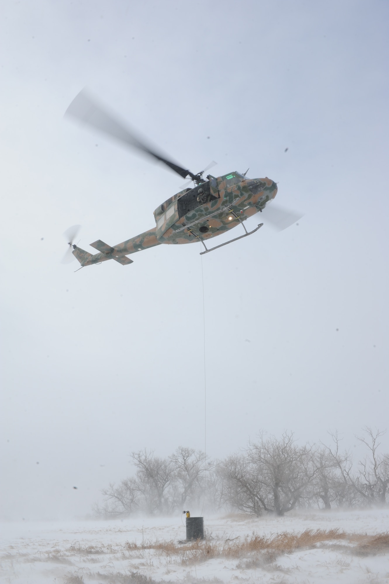 The crew of a UH1-N helicopter lowers a force penetrator into a barrel during a training mission near Minot Air Force Base, N.D., Feb. 11, 2015. The barrel was used to test the flight engineers accuracy during a simulated search and rescue mission. (U.S. Air Force photos/Senior Airman Stephanie Morris)