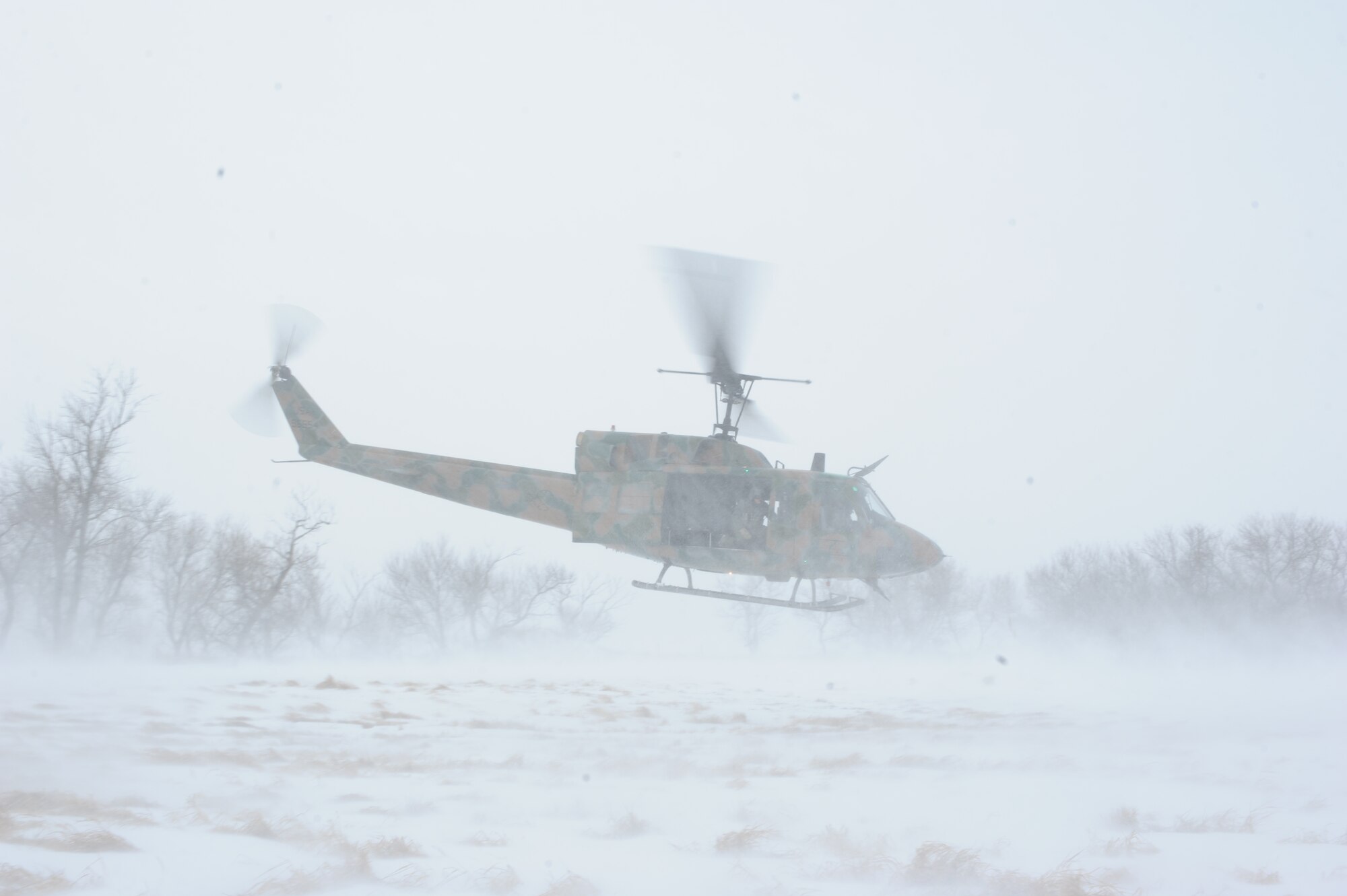 A UH1-N helicopter takes off near a stand of trees during a training mission near Minot Air Force Base, N.D., Feb. 11, 2015. During the training, the crew accounted for blowing snow and extreme low temperatures as they tested their search and rescue skills. (U.S. Air Force photos/Senior Airman Stephanie Morris)