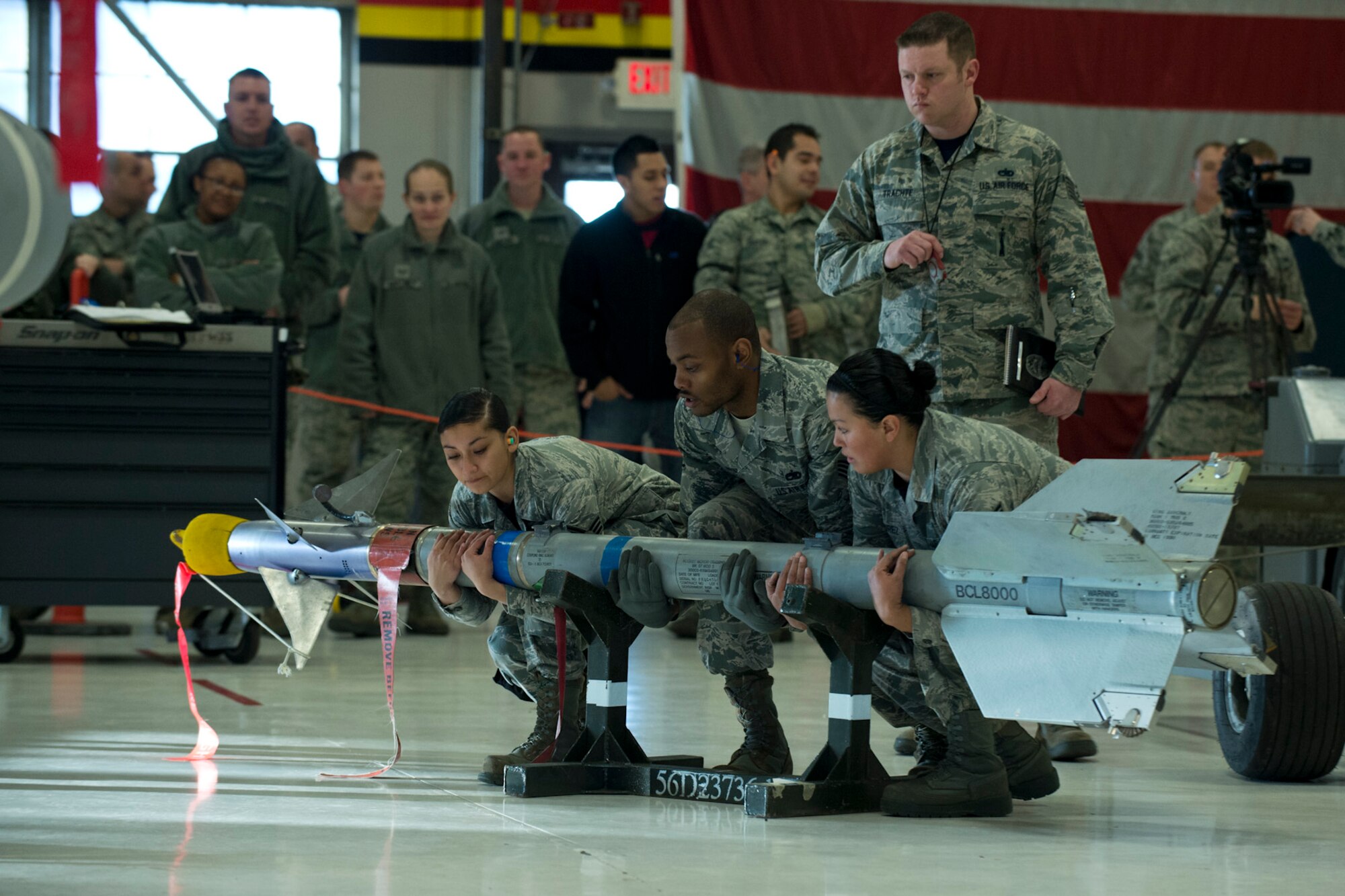 Staff Sgt. Donald Williams, 421st Aircraft Maintenance Unit weapons load crew chief and his teammates, Senior Airman Marissa Carabajal and Senior Airman Maria Ramirez, work together to lift an air-to-air missile at the weapons load competition in Hangar 37 here Feb. 13, 2015. Two 421st AMU teams and one 466th AMU team raced to see which crew will be named, "Weapons Load Crew of the Year." Winners will be announced at the Maintenance Group annual awards banquet April 11, 2015. (U.S. Air Force photo/Ronald Bradshaw)
