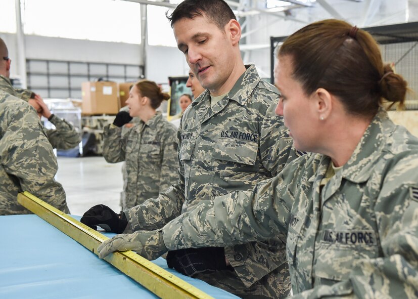 Air Force Reserve Senior Airman Tiffany Ihnot and Tech. Sgt. Patrick McCurdy, air transportation technicians assigned to the 76th Aerial Port Squadron (APS), measure a stick to aid in determining the height of pallets during the Unit Training Assembly here, Feb. 7, 2015. The pallets were measured for an upcoming Denton Mission to Honduras. U.S. Air Force photo/Senior Airman Rachel Kocin.