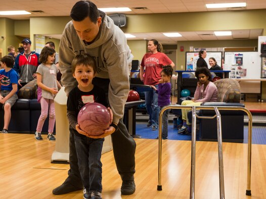 U.S. Air Force Senior Airman Mike Perron, 71st Rescue Squadron loadmaster, helps his son Patrick, bowl during the Exceptional Family Members Program’s bowling camp Feb. 11, 2015, at Moody Air Force Base, Ga. The camp was designed to be an opportunity for the children to improve social skills and patience while working as a team with other children. (U.S. Air Force photo by Airman 1st Class Ceaira Tinsley/Released)