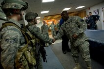 Command Sgt. Maj. Patrick Alston, senior enlisted leader for the United States Strategic Command, Offutt Air Force Base, Neb., coins two Airmen from the 91st Security Forces Group during his visit to a missile alert facility in North Dakota, Feb. 11, 2015. Alston is the senior enlisted leader for the United States Strategic Command, Offutt Air Force Base, Neb. (U.S. Air Force photo/Senior Airman Brittany Y. Bateman)