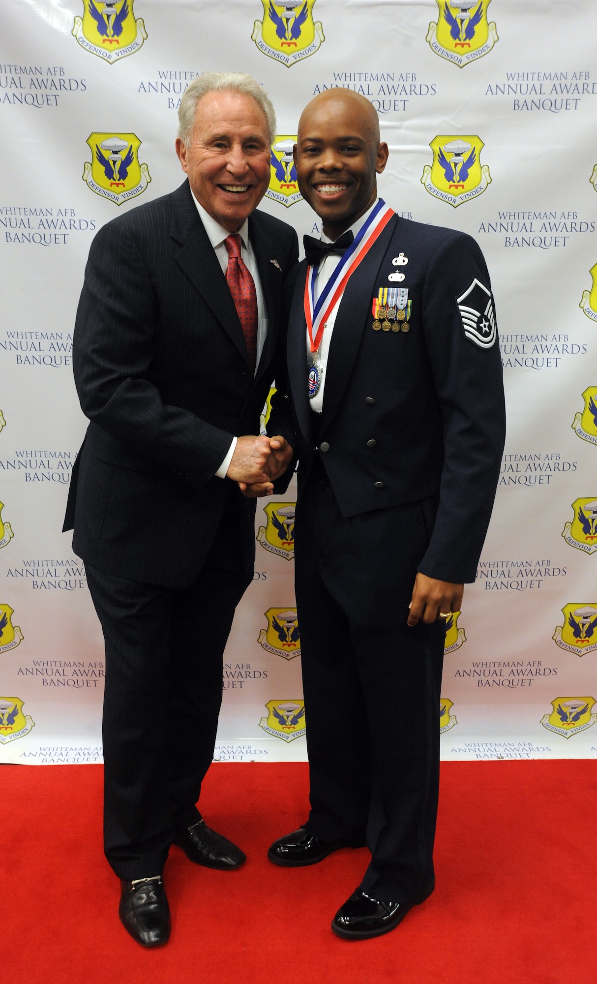 Master Sgt. Dennis Caldwell, first sergeant of the 509th Bomb Wing Command Post, and Lee Corso, an ESPN college football analyst, pose for a photo prior to the 2014 Annual Awards Banquet at the University of Central Missouri Elliot Student Union Banquet Room, Warrensburg, Mo. Feb. 6, 2015. Corso and Caldwell are fans of two different college rival football teams. (U.S. Air Force photo by Airman 1st Class Jovan Banks/Released)