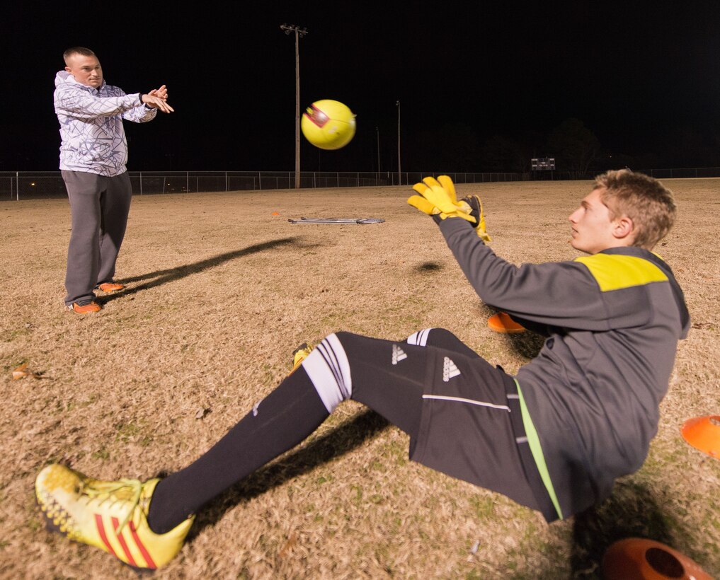 Master Sgt. Jason Butts, left, a 116th Air Control Wing ground explosives safety craftsman, tosses a soccer ball to one of the players he coaches during a practice in Warner Robins. Butts topped thousands of coaches from 12 states to be named Region 3 Boys Recreational Soccer Coach of the Year. (U.S. Air Force photo by Master Sgt. Roger Parsons)