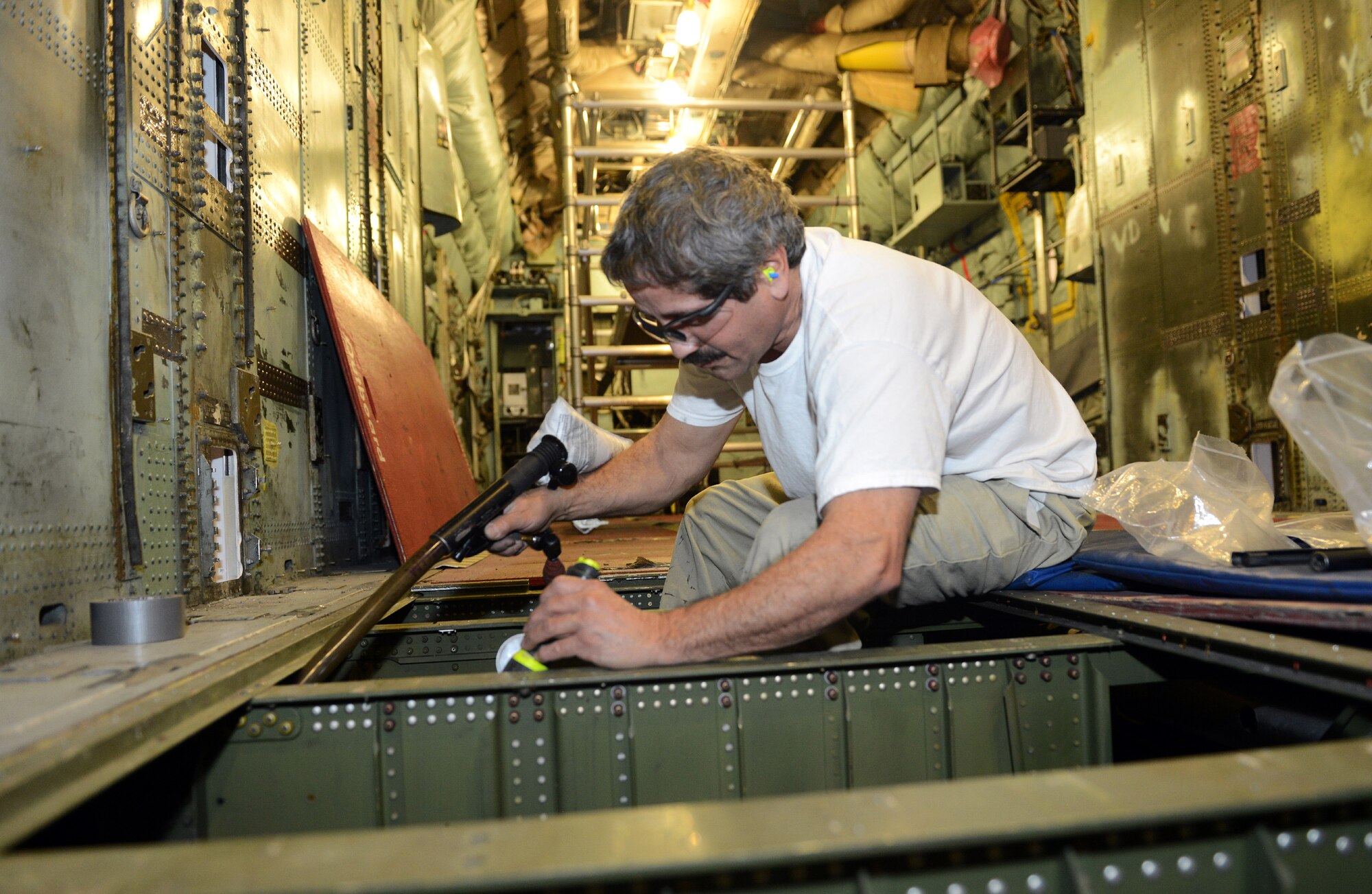 Carlos Melendez, 560th Aircraft Maintenance Squadron sheet metal mechanic, replaces floor boards in the cargo area of a C-130H. (U.S. Air Force photo by Tommie Horton)