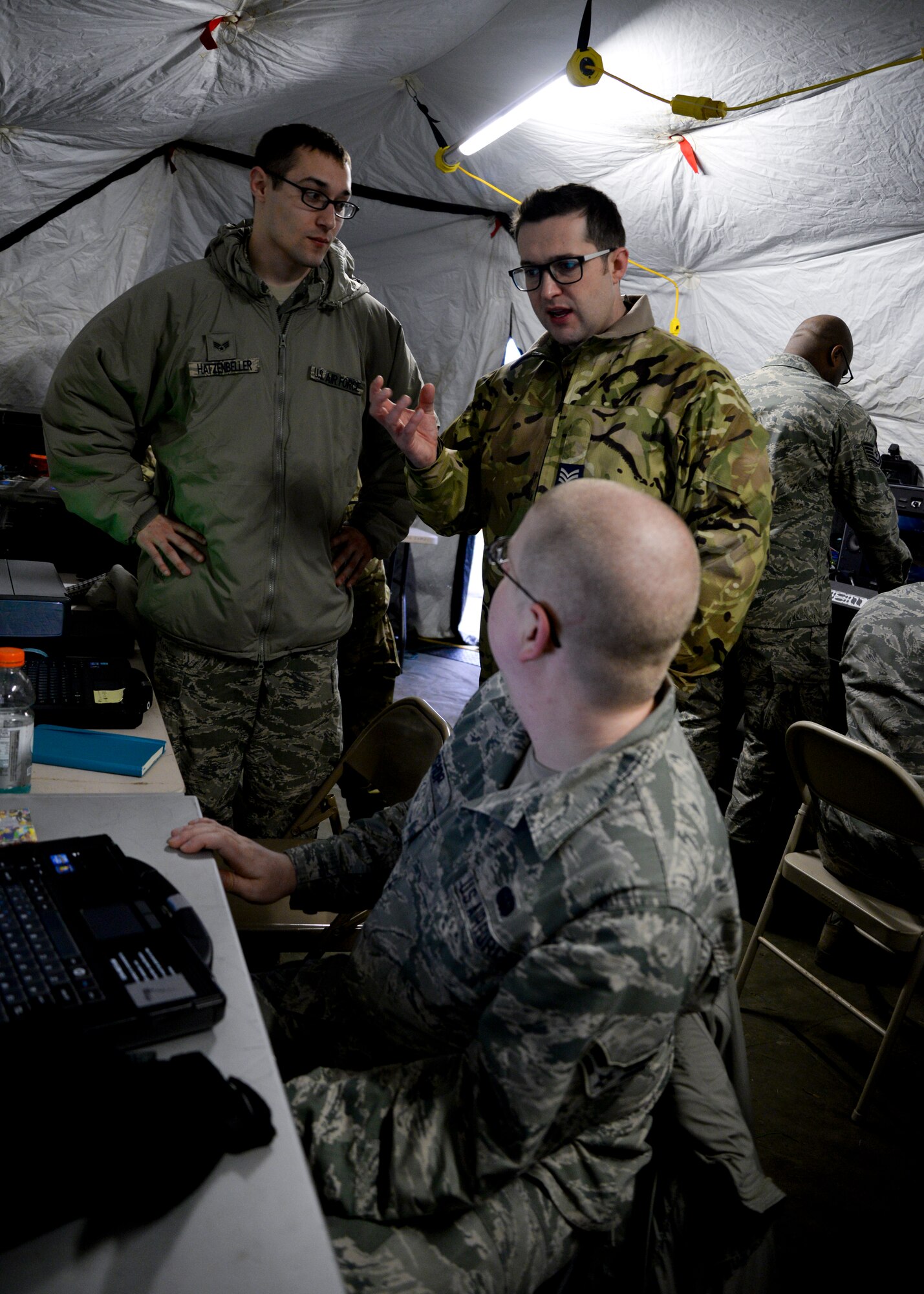 U.S. Air Force Senior Airman Joshua Hatzenbeller, left, 352nd Special Operations Support Squadron cyber transport systems technician from Cumberland, Wis., and U.S. Air Force Airman 1st Class Charles Bishop, front, 352nd SOSS radio frequency transmissions technician from Jonesboro, Ark., speaks with Royal Air Force Sgt. Paul Matthews, 90th Signals Unit information communication technology technician from Middlesbrough, England, Jan. 28, 2015, on RAF Mildenhall, England. Matthews was one of six personnel visiting the base to further collaboration with the 352nd SOSS and test out new equipment. (U.S. Air Force photo by Senior Airman Victoria H. Taylor/Released)