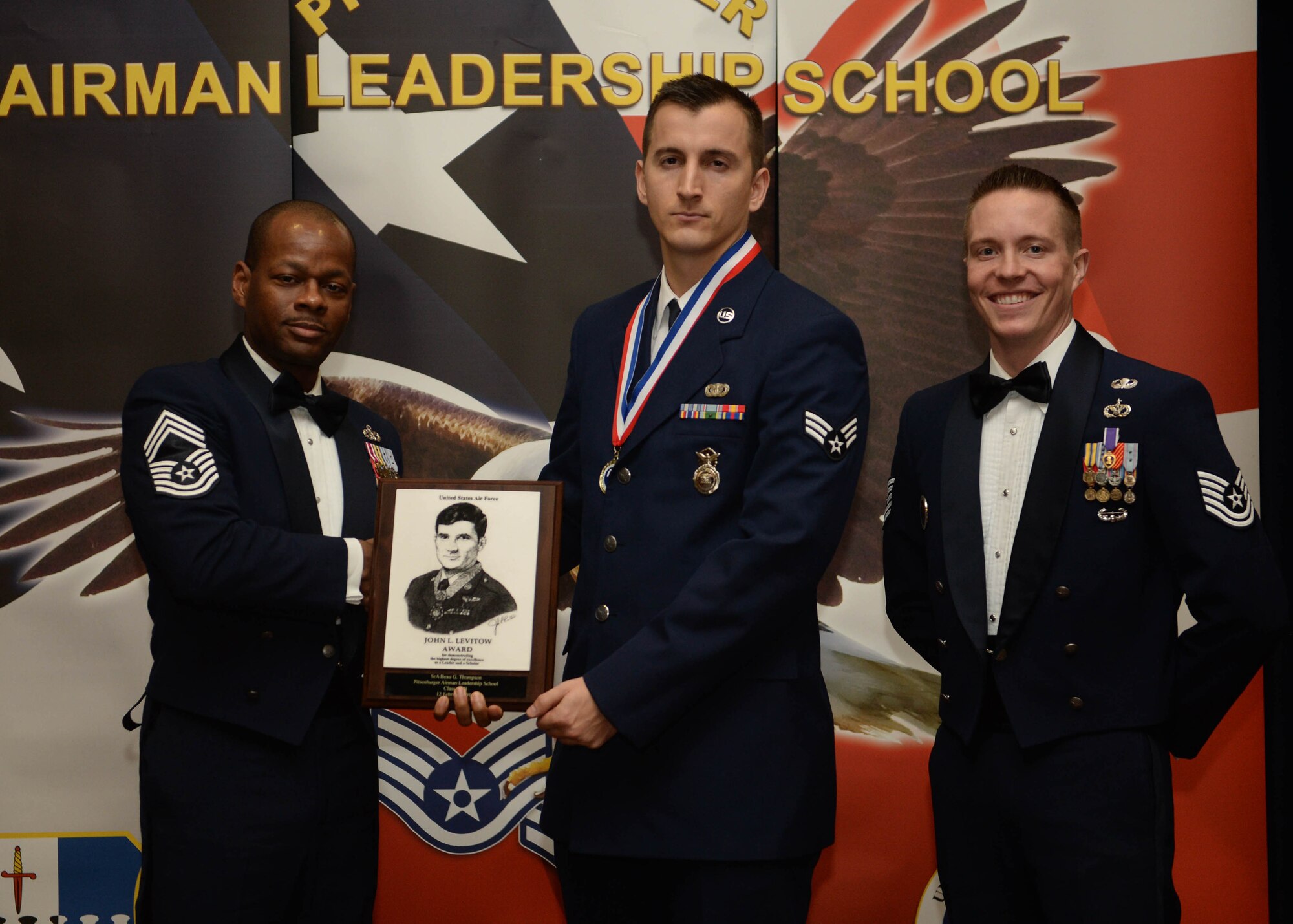 U.S. Air Force Chief Master Sgt. Shawn Lee, 52nd Civil Engineer Squadron superintendent, left, and U.S. Air Force Tech. Sgt. Kalob Hinners, Airman Leadership School acting commandant, right, present U.S. Air Force Senior Airman Beau Thompson, 703rd Munitions Support Squadron, center, with the John L. Levitow award during the ALS Class 15-B graduation ceremony at Club Eifel on Spangdahlem Air Base, Feb. 12, 2015. The Levitow award is presented to the student who demonstrated the most outstanding leadership and scholastic qualities based on academic performance and assignment of points by peers and instructors. (U.S. Air Force photo by Airman 1st Class Timothy Kim/Released)