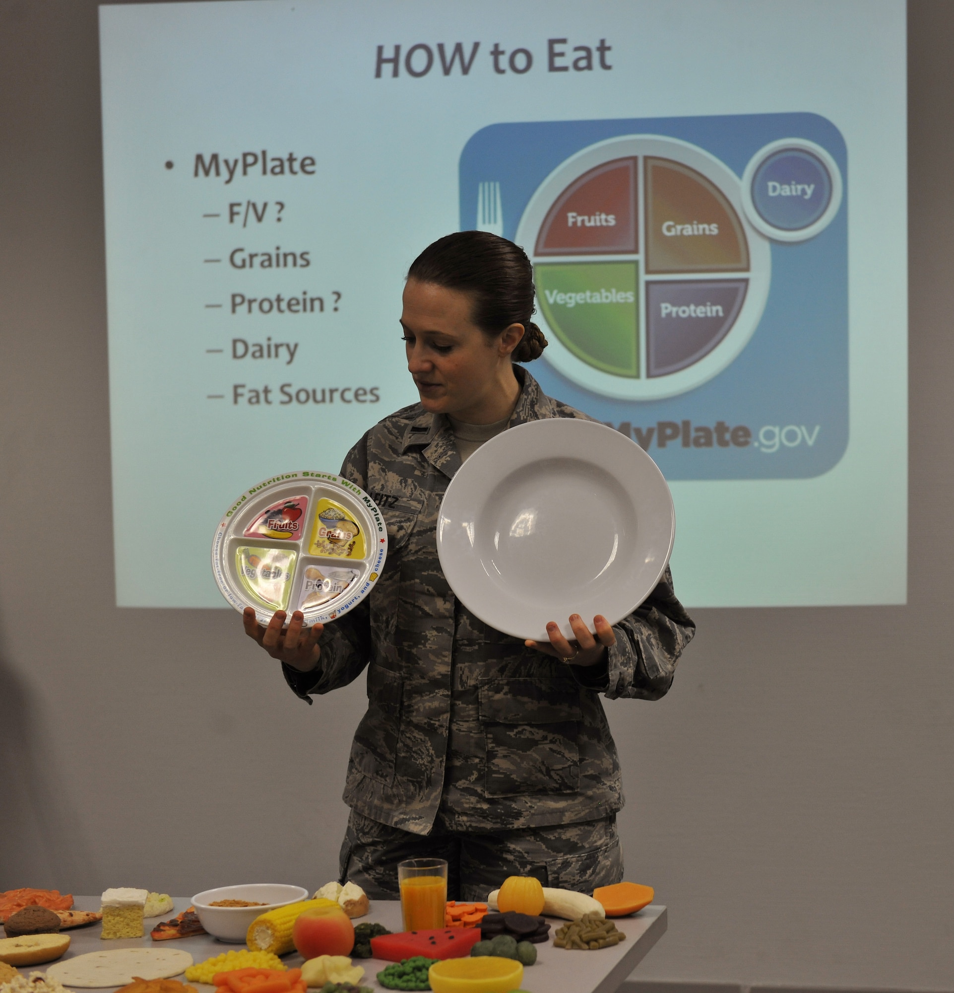 First Lt. Lindsey Leitz, Health Promotion nutrition program manager, demonstrates the difference between a 9-inch plate, which would provide proper proportions when eating, to the 12-inch plates served at many restaurants, during the Healthy Living Class at Ramstein Air Base, Feb. 9, 2015. Leitz teaches about the MyPlate program that breaks down a 9-inch plate into four sections for fruits, vegetables, grains and protein. (U.S. Air Force photo/A1C Tryphena Mayhugh)