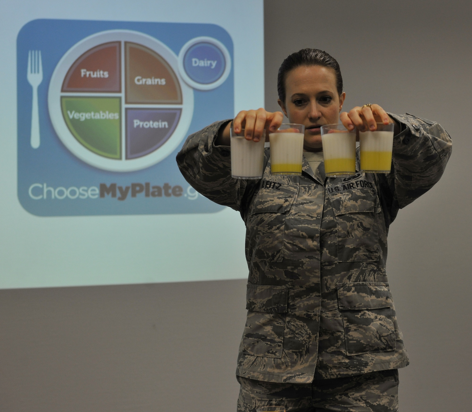 First Lt. Lindsey Leitz, Health Promotion nutrition program manager, explains the varying levels of fat contained in different types of milk, ranging from whole to skim, during the Healthy Living Class at Ramstein Air Base, Germany, Feb. 9, 2015. According to Leitz, the fat content of some milk has been the most shocking information for class attendees to hear. (U.S. Air Force photo/A1C Tryphena Mayhugh))