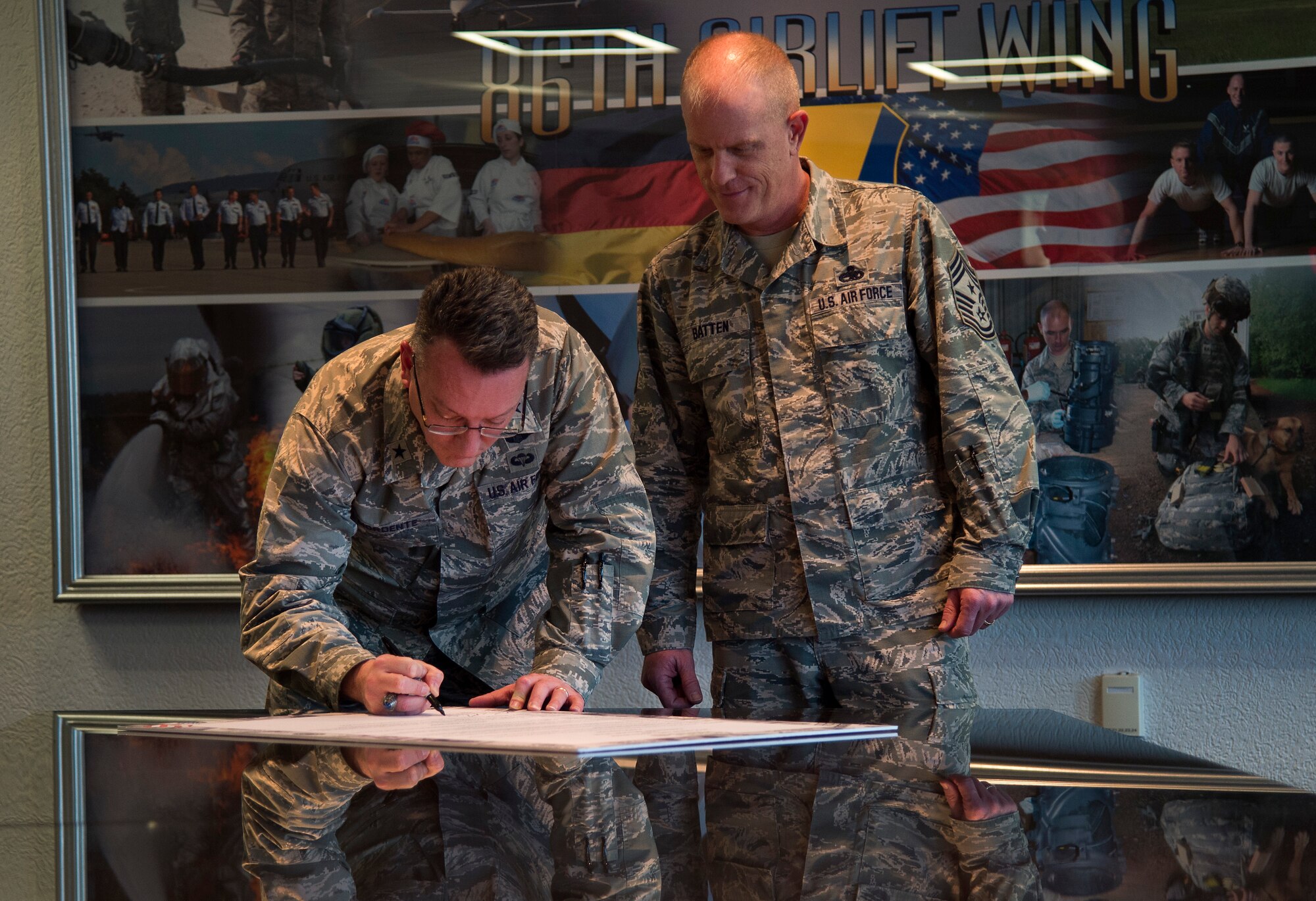 Brig. Gen. Patrick X. Mordente, 86th Airlift Wing commander, signs a Military Saves Week proclamation with Chief Master Sgt. Frank Batten III, 86th AW command chief looking on at Ramstein Air Base, Germany, Feb. 13, 2015. Military Saves, a component of the nonprofit America Saves and a partner in the Department of Defense’s Financial Readiness Campaign, seeks to motivate, support and encourage military families to save money, reduce debt and build wealth. The proclamation declares Feb. 23 to 27 as Military Saves Week, encouraging service members to set financial goals. (U.S. Air Force photo/Senior Airman Damon Kasberg)