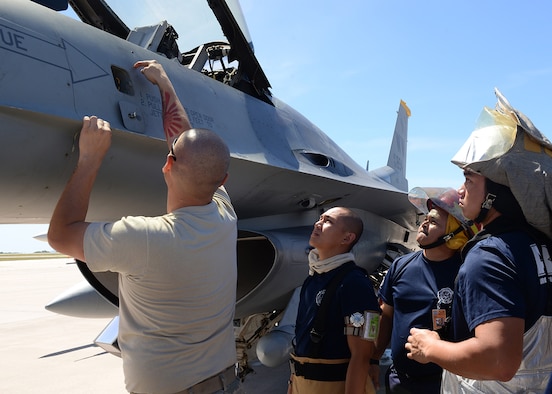 An F-16 maintainer deployed from the 35th Fighter Wing out of Misawa Air Base, Japan, shows Saipan firefighters various hazardous points on a F-16 Fighting Falcon during training Feb. 12, 2015, at the Saipan International Airport, Saipan in the Commonwealth of Northern Marianas Islands approximately 130 miles north of Guam. The training was geared towards preparing Saipan first responders for a runway emergency involving the F-16. (U.S. Air Force photo by Senior Airman Cierra Presentado/Released) 