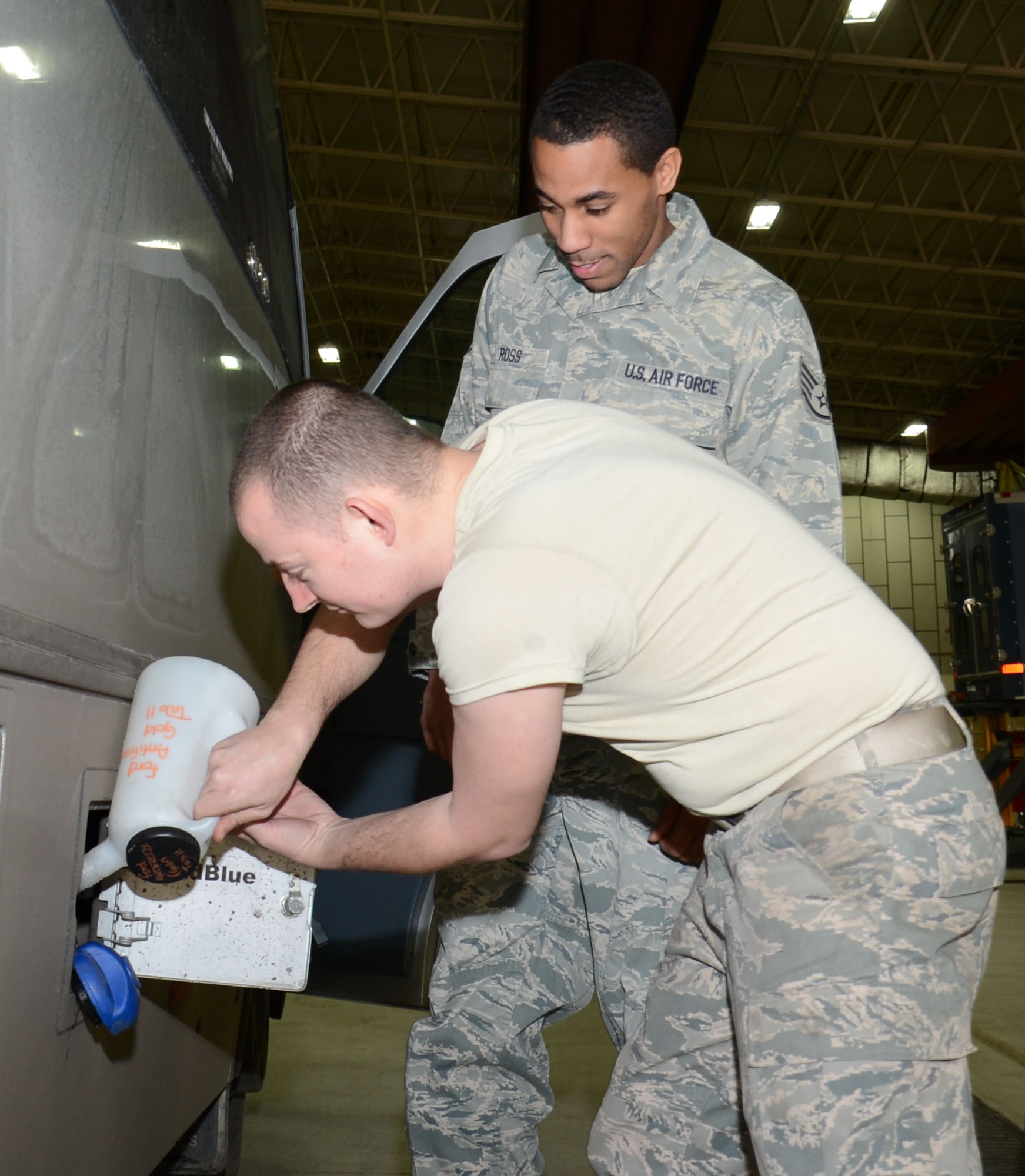 U.S. Air Force Staff Sgt. Jayme Ross, back, 100th Logistics Readiness Squadron Allied Trades NCO in charge from Hartford, Conn., oversees U.S. Air Force Staff Sgt. Matthew Mason, 100th LRS Vehicle and Equipment Maintenance craftsman from Eatonton, Ga., adding a fuel additive which eliminates the production of excessive exhaust fumes and pollutants into the air on one of the flight’s recently acquired buses Feb. 6, 2015, on RAF Mildenhall, England. This additive is important because it ensures the flight’s ability to minimize their environmental impacts in the United Kingdom while sustaining an effective military presence in the European Theater in support of the sole aerial refueling and special operations mission. (U.S. Air Force photo by Gina Randall/Released)