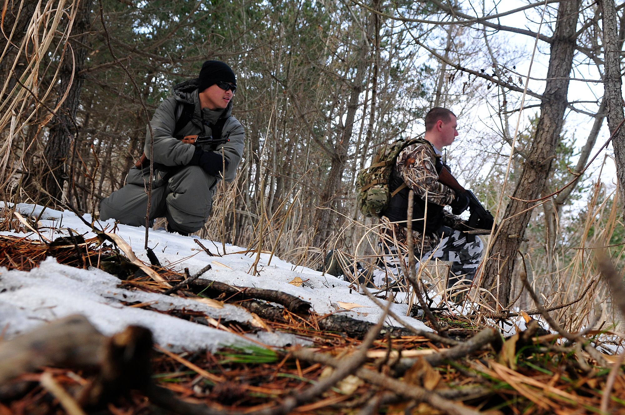 U.S. Air Force Staff Sgt. Bobby Chanthaphouvong and James Thompson, 35th Operations Support Squadron opposing forces members, halt their pursuit of a downed pilot to listen for any signs of distress during Survival, Evasion, Resistance and Escape training for pilots at the Draughon Range outside Misawa Air Base, Japan, Feb. 12, 2015. As members of opposing forces, Chanthaphouvong and Thompson were tasked with tracking downed pilots and capturing them for mock interrogation. (U.S. Air Force photo by Senior Airman Jose L. Hernandez-Domitilo)