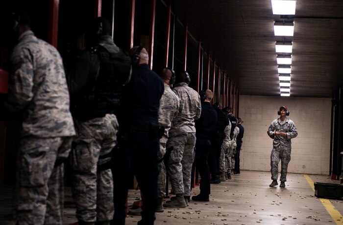 JOINT BASE CHARLESTON, S.C. – A 628th Security Forces Squadron Combat Arms Training and Maintenance instructor, walks along the firing range yelling commands to Airmen during an M-4 carbine qualifying session at night at the Combat Arms Training and Maintenance firing range, Feb. 11, 2015, on Joint Base Charleston, S.C. Airmen wear two forms of ear protection to prevent damage to their eardrums, prompting CATM instructors to yell commands so all can hear. (U.S. Air Force photo/ Senior Airman Dennis Sloan)