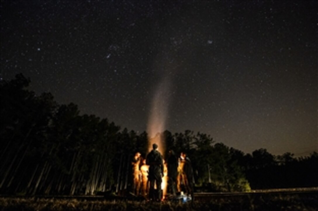 Airmen relax by a camp fire after completing a day of training during Exercise Scorpion Lens 15 on North Auxiliary Airfield in the city of North, S.C., Feb., 11, 2015. 

