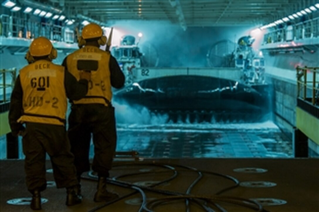 Navy Petty Officer 2nd Class Adrian Martinezgarcia, left, instructs Petty Officer 2nd Class Jerry Williams as he directs a landing craft air cushion into the well deck of the amphibious assault ship USS Essex in the Pacific Ocean, Feb. 12, 2015. The Essex is underway completing certifications in preparation for an upcoming deployment. 
