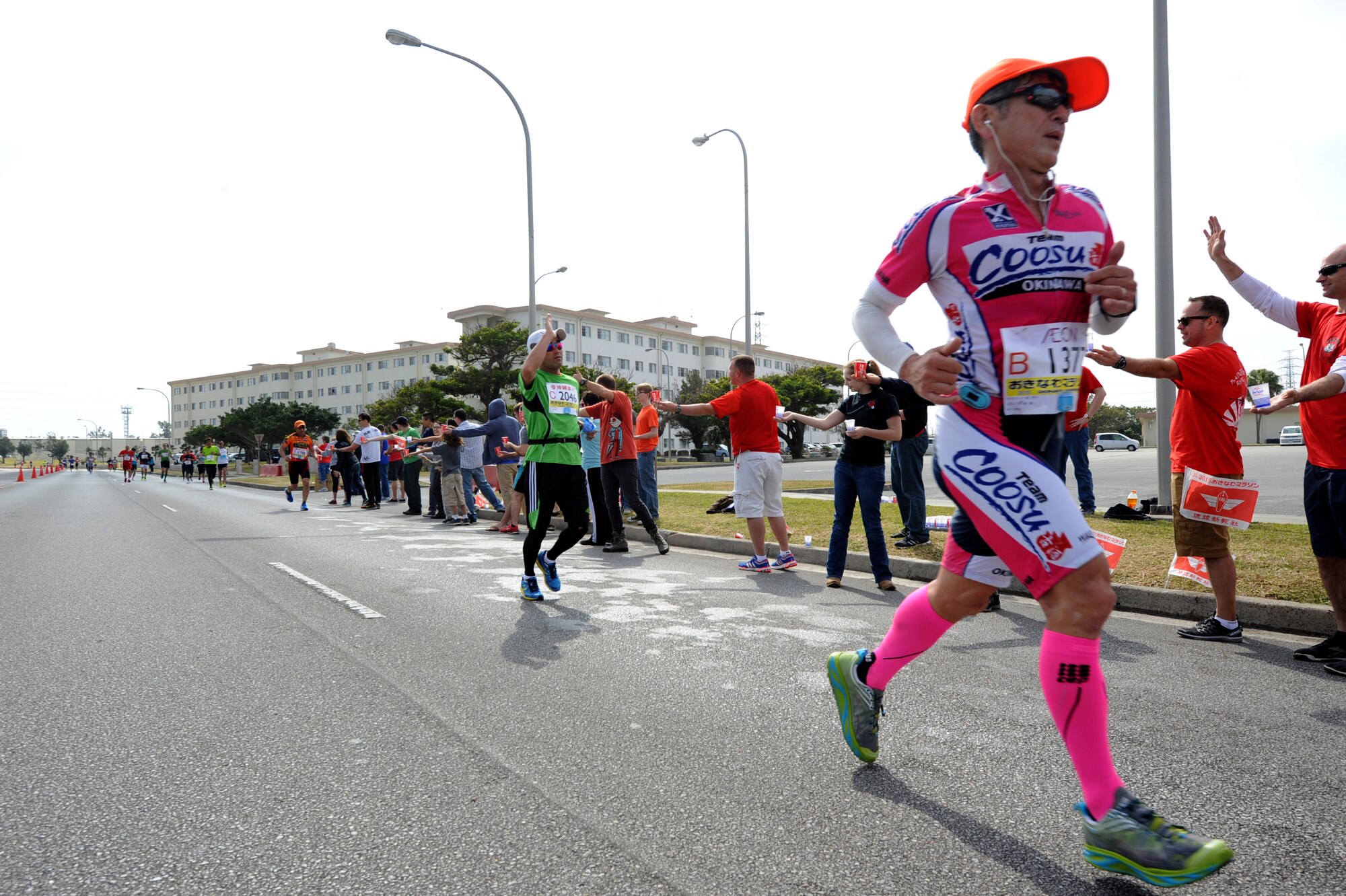 Runners are cheered on by volunteers during the 2015 Okinawa Marathon as follow the route through Kadena Air Base, Feb. 15, 2015.  More than 11,000 runners, including 300 U.S. service members, ran the 42-km race to the cheers from hundreds of volunteers. This was the 23rd year Kadena opened a 2.8 km route from Gate 2 to Gate 5 for the Okinawa Marathon. (U.S. Air Force photo by Airman 1st Class Zackary A. Henry)