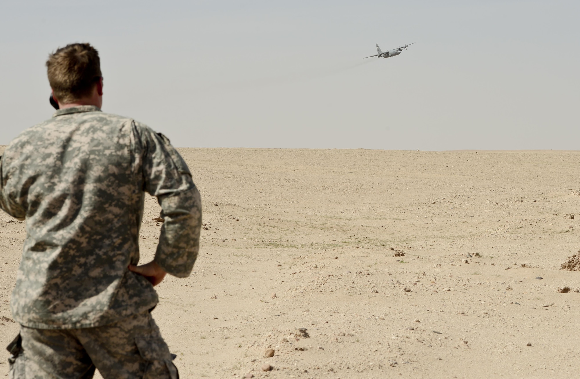 SOUTHWEST ASIA - An Airman with the 82nd Expeditionary Air Support Operations Squadron calls in a resupply drop from a C-130 during drop zone control officer training Feb. 10, 2015. The C-130 is from the 737th Expeditionary Airlift Squadron here and helped 82nd EASOS Airmen practice calling in aircraft for resupply drops. (U.S. Air Force photo by Tech. Sgt. Jared Marquis/released)