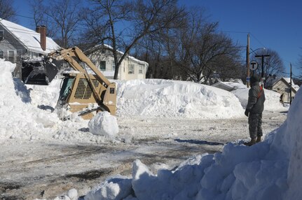 Soldiers from the Massachusetts National Guard’s 379th Engineer Company of Buzzards Bay clear snow caused by Winter Storm Neptune at Bellevue Station, here on Feb. 16th, 2015. They assisted the Massachusetts Bay Transit Authority and the department of public works in clearing station parking and reducing the size of snow banks. 