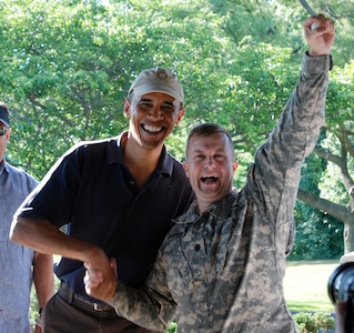 U.S. President Barack Obama shakes hands with newly-promoted Lt. Col. Scott Bartlett as Bartlett displays a special presidential golf ball presented to him by Obama.