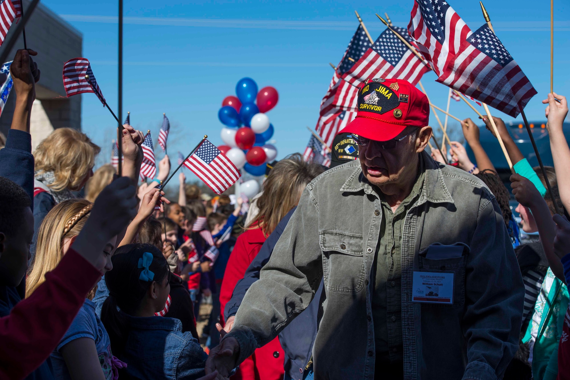 William Schott, Iwo Jima survivor, walks through a gauntlet outside Sheppard Elementary School at Sheppard Air Force Base, Texas, Feb. 13, 2015. Children from the school met with WWII veterans during the Iwo Jima Survivors 70th Reunion. (U.S. Air Force photo by Senior Airman Kyle Gese/Released)