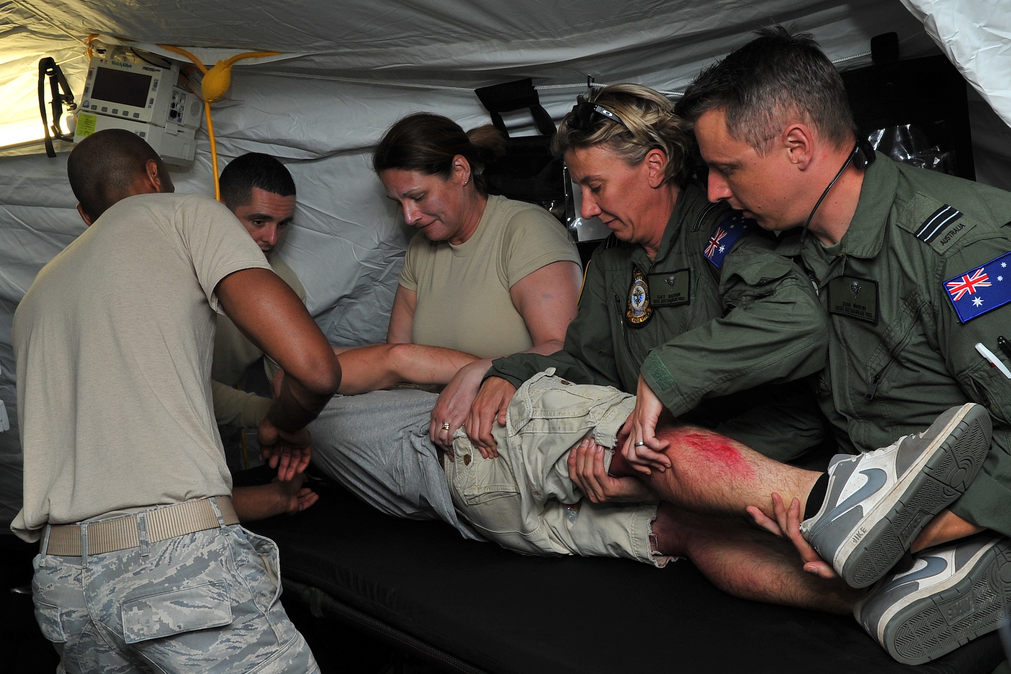 U.S. Air Force and Royal Australian Air Force medical experts assess a critical care patient for additional wounds at an expeditionary intensive care unit at Sinapalo, Rota, Feb. 16, 2015. Exercise COPE NORTH 15 enhances humanitarian assistance and disaster relief crisis response capabilities between six nations and lays the foundation for regional cooperation expansion during real-world contingencies in the Asia-Pacific Region. (U.S. Air Force photo by Staff Sgt. Melissa B. White/Released)
