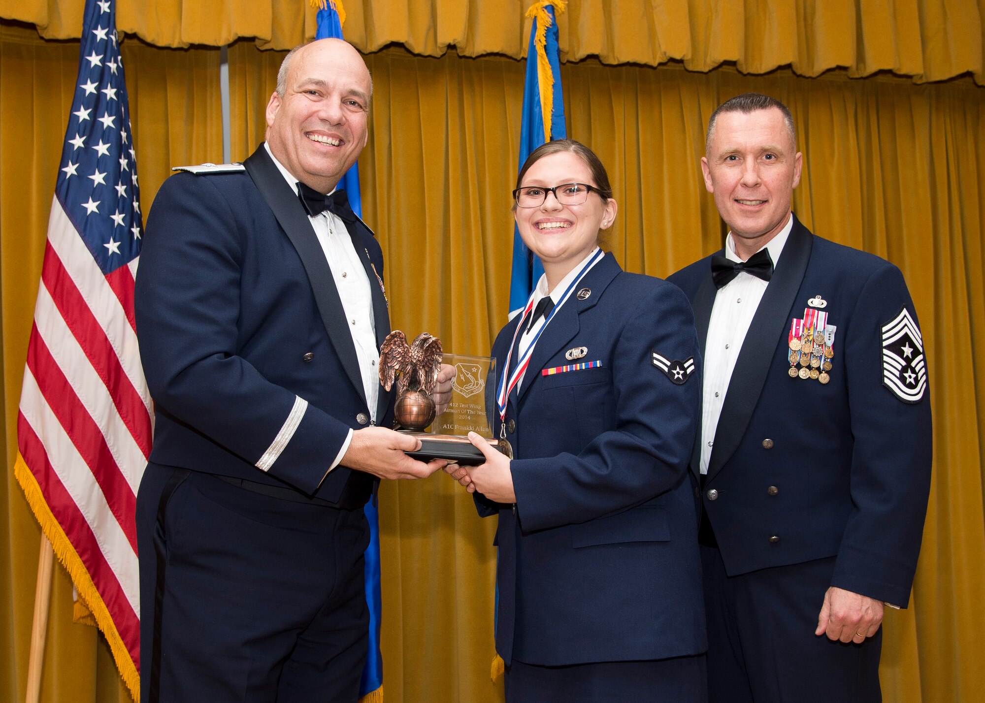 Brig. Gen. Michael T. Brewer, 412th Test Wing commander (left), and Chief Master Sgt. David Smith, 412th TW command chief (right), congratulate Airman 1st Class Frankki Allen, 412th Operations Group, who is the 412th Test Wing Airman of the Year. The wing's annual awards banquet was held Feb. 13 at Club Muroc. (U.S. Air Force photo by Ethan Wagner)
