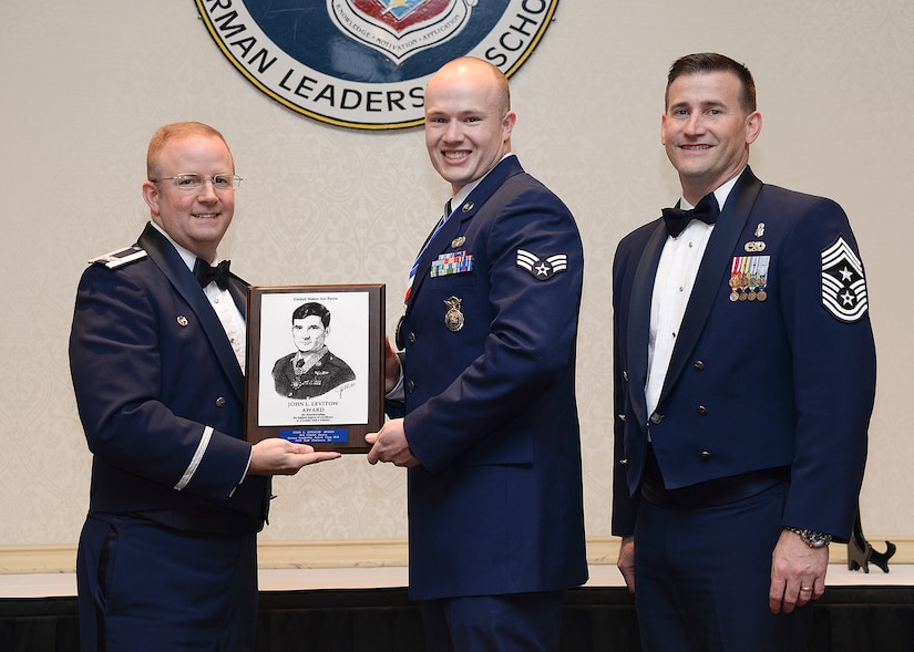 Col. Jeffrey DeVore, Joint Base Charleston commander, and Chief Master Sgt. Mark Bronson, 628th Air Base Wing command chief, present Senior Airman Charles Benton, 628th Security Forces Squadron, the John Levitow Award during the Airman Leadership School Class 15-B graduation ceremony Feb. 12, 2015, at JB Charleston - Air Base, S.C. The Levitow Award is awarded for a student's exemplary demonstration of excellence, both as a leader and scholar. (U.S. Air Force photo by Tech. Sgt. Rasheen Douglas)