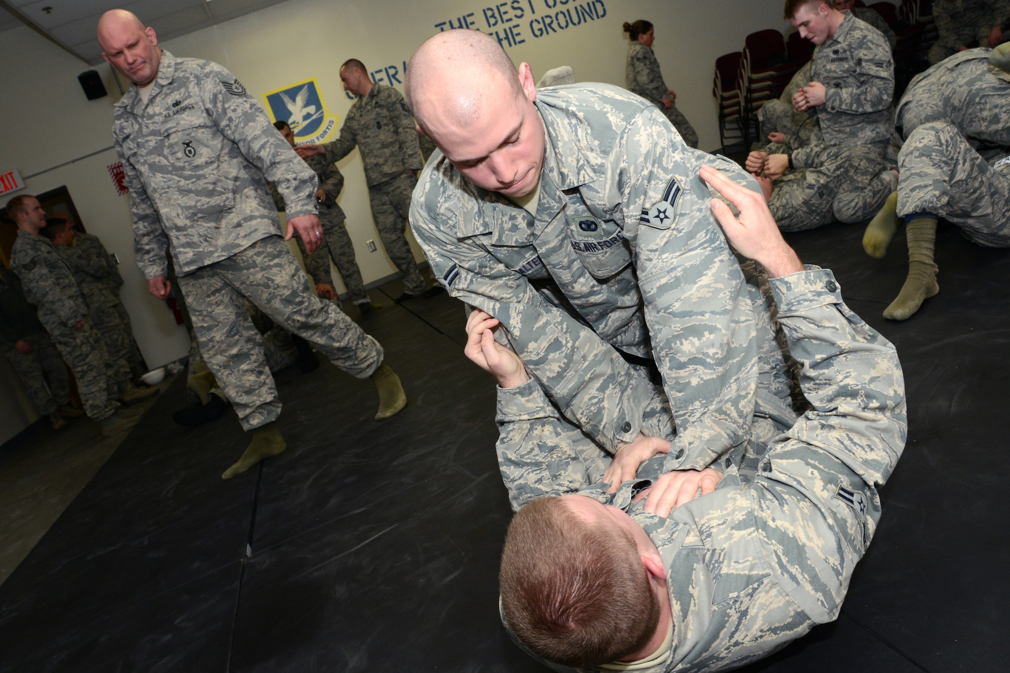 Airmen First Class Nathaniel Salter (top) and Zachary Crawford (bottom), both security forces personnel with the 103rd Security Forces Squadron, practice hand-to-hand ground combat maneuvers during an Air Force combatives class Feb. 7, 2015, at Bradley Air National Guard Base, East Granby, Conn. Tech. Sgt. Jerry Lashway, squad leader, 103rd Security Forces Squadron, looks on analyzing the Airmen’s technique. (U.S. Air National Guard photo by Tech. Sgt. Joshua Mead/released)