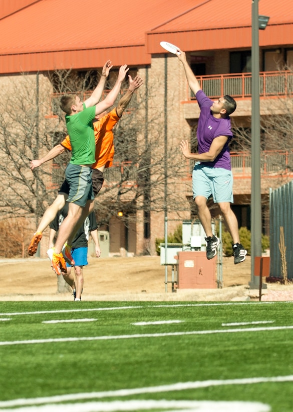 PETERSON AIR FORCE BASE, Colo. –Jake Hume (purple shirt) snatches a Frisbee disc from the air and out of the clutches of Mike Lauritzen (green shirt) and Andrew Wind (orange shirt) during an Ultimate Frisbee match on the base football field Feb. 13. Myers and Wind are part of a group of base-wide “Ultimate” enthusiasts who have been playing these twice-weekly matches for the past two years. (U.S. Air Force photo by Staff Sgt. J. Aaron Breeden)