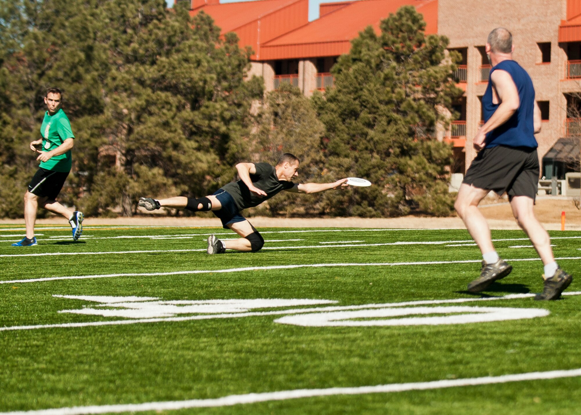PETERSON AIR FORCE BASE, Colo. – Jason Brown (left) and John Schoh II (right) watch as Andy Muser makes a diving catch during an Ultimate Frisbee match on the base football field Feb. 13. Brown, Schoh and Muser are part of a group of base-wide “Ultimate” enthusiasts who have been playing these twice-weekly matches for the past two years. (U.S. Air Force photo by Staff Sgt. J. Aaron Breeden)