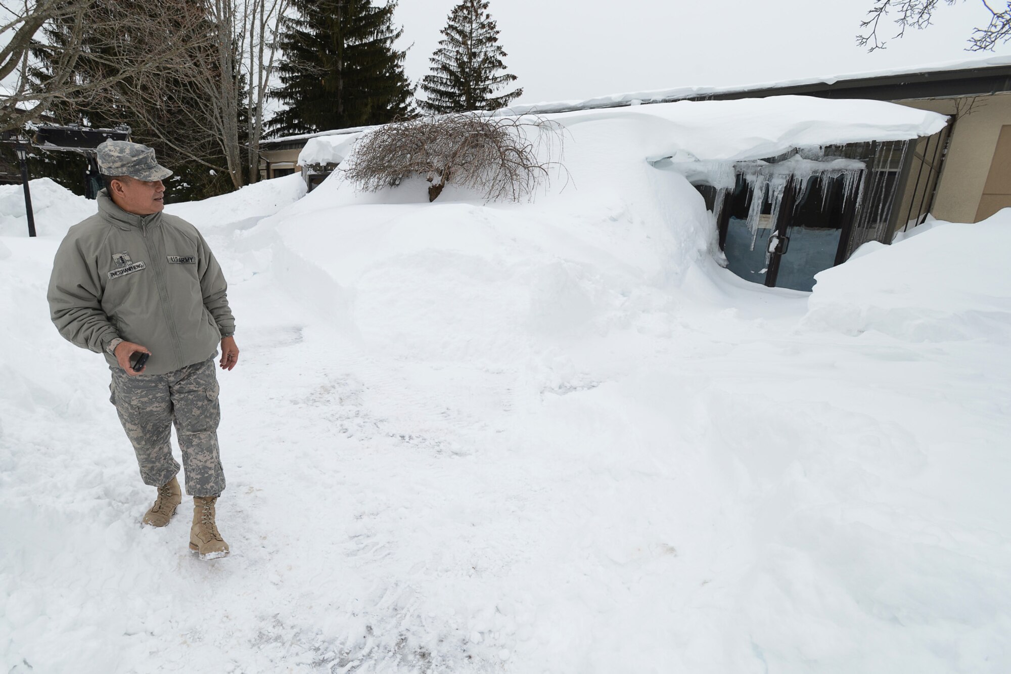 U.S. Army Reserve Chief Warrant Officer 4 Souvanno Phetchanpheng, Regional Training Center maintenance technical advisor, assigned to Fort Devens, Mass. looks at the front of the snow-covered Hanscom Thrift Store, Feb. 17. The snow from this weekend’s storm was piled so high that Phetchanpheng had to wait for a small front end loader to clear a customer entrance before he could enter the building.(U.S. Air Force photo by Jerry Saslav)