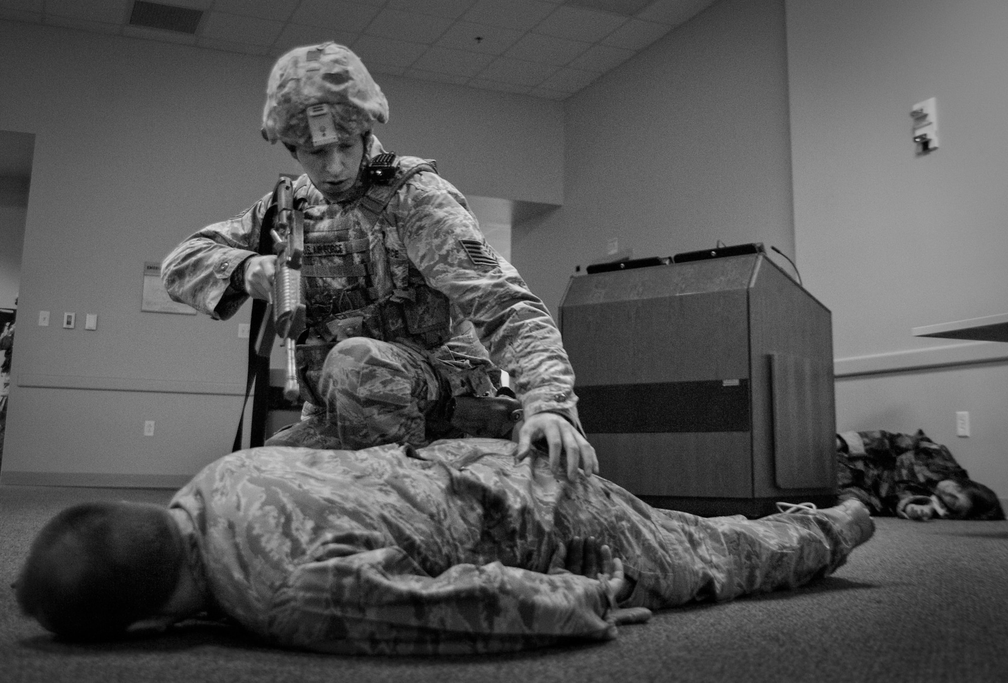 Tech. Sgt. Brent Young, 96th Security Forces Squadron, examines a simulated gunshot victim with a spinal injury during an active shooter exercise Feb. 4 at Duke Field, Fla.  The Airmen entered the building to apprehend the suspect, assess the wounded and report back information to the emergency responders. (U.S. Air Force photo/Samuel King Jr.)