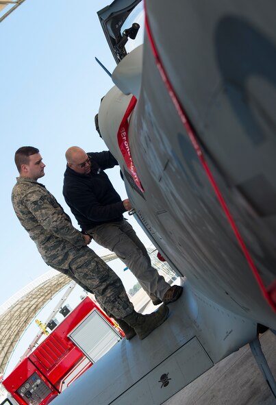 U.S. Air Force Senior Airman Joseph Bagnasco, 23d Civil Engineer Squadron driver operator, receives instruction from Wayne Krieter, Sierra Nevada Corporation aircraft inspector, during A-29 Super Tucano egress training Feb. 12, 2015, at Moody Air Force Base, Ga. Krieter showed Bagnasco the different parts needed to shut down the aircraft and rescue an incapacitated pilot. (U.S. Air Force photo by Airman 1st Class Ceaira Tinsley/Released)