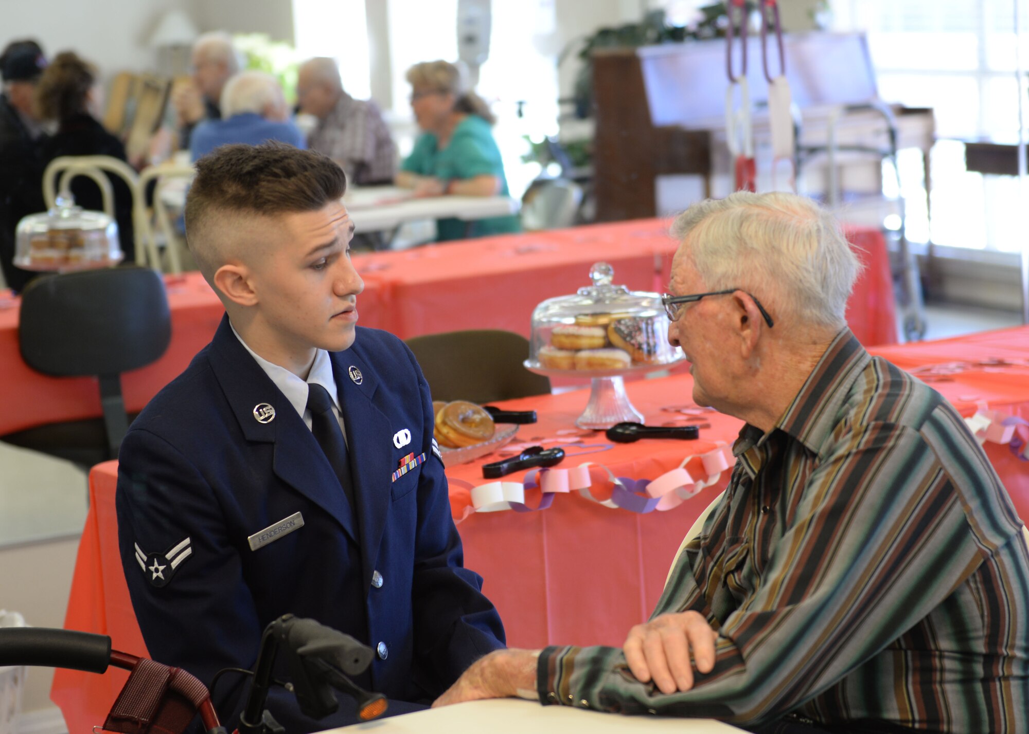 ALTUS, Okla. – U.S. Air Force Airman 1st Class Trever Henderson, 97th Air Mobility Wing emergency actions controller, talks with veteran Red Drury while volunteering with Valentines for Vets in the Tamarack Assisted Living Center, Feb. 12, 2015. Airmen spent their morning distributing cards and talking with veterans about their time serving the military. (U.S. Air Force photo by Airman 1st Class J. Zuriel Lee/Released)