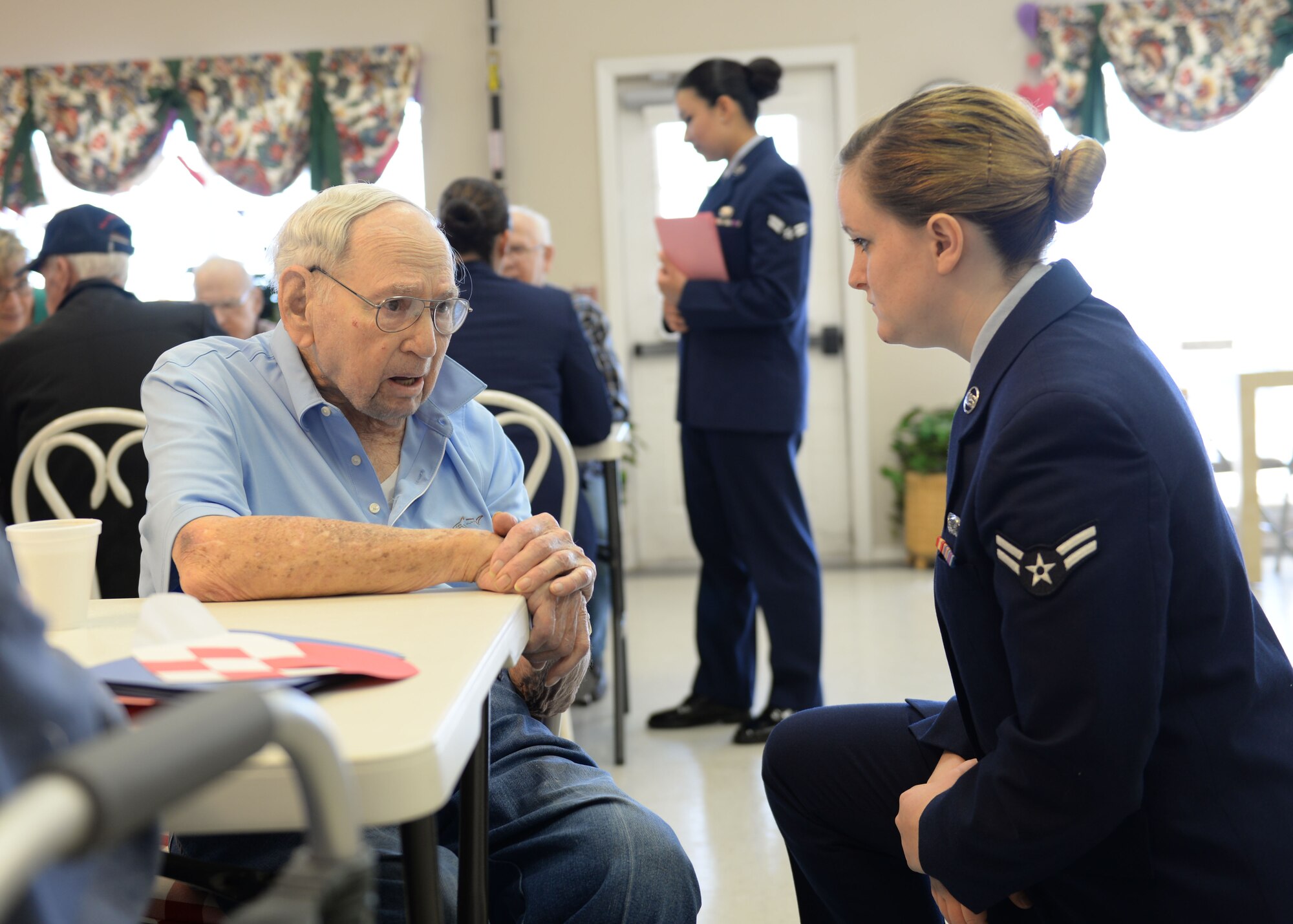 ALTUS, Okla. – U.S. Air Force Airman 1st Class Susan Good, 97th Air Mobility Wing administrator, talks with veteran Les Autry while volunteering with Valentines for Vets in the Tamarack Assisted Living Center, Feb. 12, 2015. Airmen stationed at Altus Air Force Base visited veterans in four assisted living facilities to distribute cards and talk with the veterans. (U.S. Air Force photo by Airman 1st Class J. Zuriel Lee/Released)