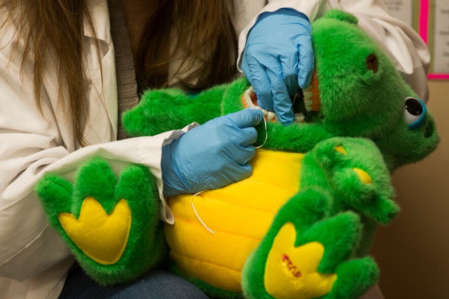 Dawn Greene, 23d Aerospace Medicine Squadron dental assistant, flosses Dino’s teeth during a demonstration at the Child Development Center Feb. 10, 2015, at Moody Air Force Base, Ga. Greene advised CDC students to floss and brush their teeth twice a day. (U.S. Air Force photo by Airman 1st Class Dillian Bamman/Released)