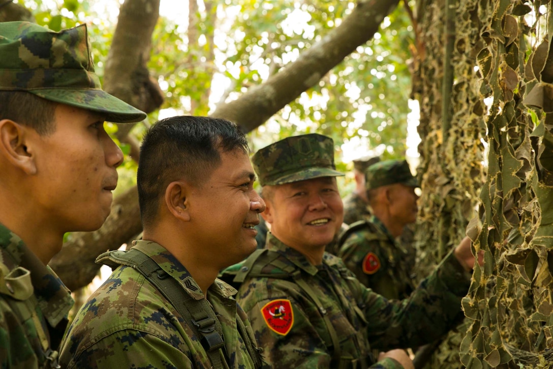 Royal Thai Marines watch U.S. Marines passing around fruit Feb. 8 at Ban Chan Krem, Thailand, during exercise Cobra Gold 2015. The excitement of the U.S. Marines brought joy to the Thai Marines who taught a lesson in jungle survival. (U.S. Marine Corps photo by Cpl. Isaac Ibarra/Released)