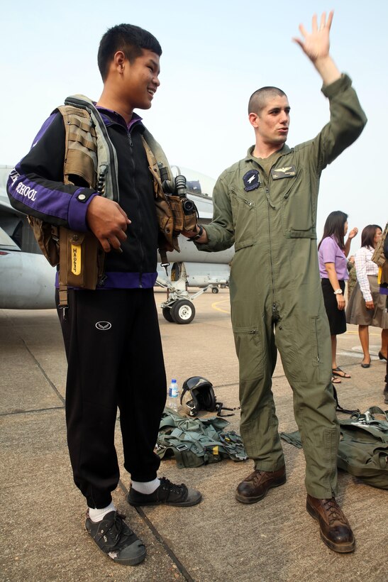U.S. Marine pilot Capt. Ernie Drake shows Yothinnukun School student, Nattasit Attapolpisarn, the gear he uses when operating an aircraft during an open house held by Royal Thai Air Force Wing 1 and U.S. Marines at Royal Thai Air Force Base Korat during Exercise Cobra Gold 2015, Feb. 13. Students also observed demonstrations of the Marine Corps Martial Arts Program, Explosive Ordnance Disposal, Aircraft Rescue Firefighters, and Navy Corpsmen basic medical procedures. Drake is with Marine All-Weather Fighter Attack Squadron 533, currently attached to Marine Aircraft Group 12, 1st Marine Aircraft Wing, III Marine Expeditionary Force in Iwakuni, Japan, under the Unit Deployment Program. Cobra Gold 2015 is a Thailand /United States co-sponsored, multinational and joint theater security cooperation exercise, conducted annually in the Kingdom of Thailand, with 25 nations participating. This year there is an increased focus on Humanitarian Civic Action, community engagement, and medical activities to support the needs and humanitarian interests of civilian populations around the region. For more information on exercise Cobra Gold, please visit the official Facebook page at http://www.facebook.com/ExerciseCobraGold.